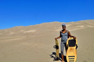 Holding a sandboard and sand sled (Colorado)